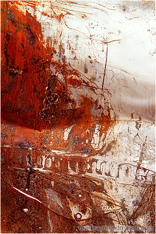 Fine art photograph of white paint and red rust on the surface of a folded, puntured piece of sheet metal