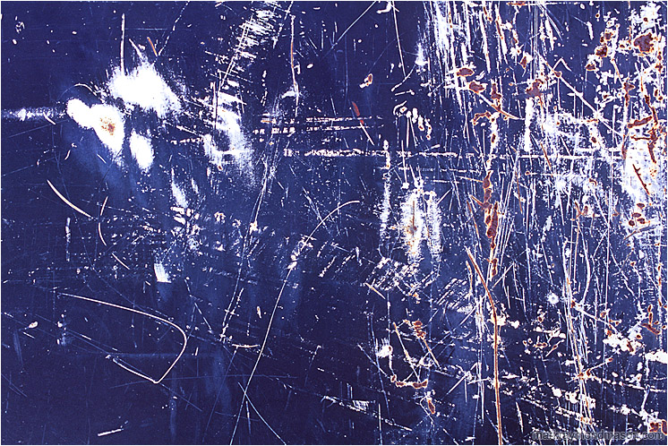 Primer, Paint, Rust: Calgary, AB, Canada (2008-00-00) - Abstract photograph of chaotic white and rusty scratches on the surface of a dark blue painted piece of scrap metal