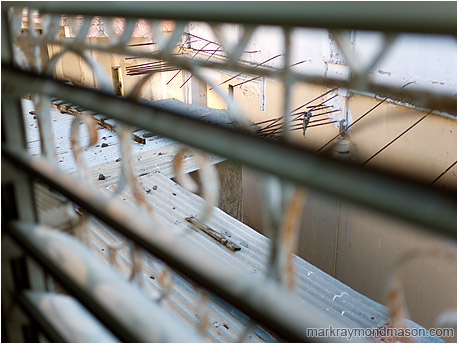 Abstract photograph of blurred window bars guarding an abandoned courtyard between aging concrete buildings