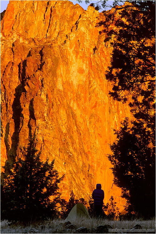 Terri, Tent, Orange Rock Sunrise: Smith Rocks, OR, USA (2002-00-00) - Lifestyle photo of a silhouetted woman and her tent, in front of a wall of bright orange, sunlit rock