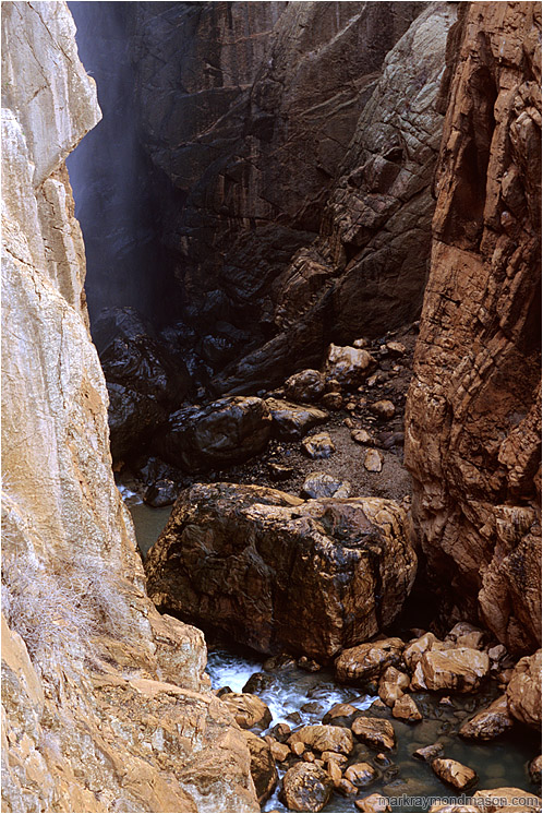 River Canyon, Mist: Near El Chorro, Spain (2006-00-00) - Fine art nature photograph of water and mist in a deep slot canyon, with steep cliffs of orange and black rock