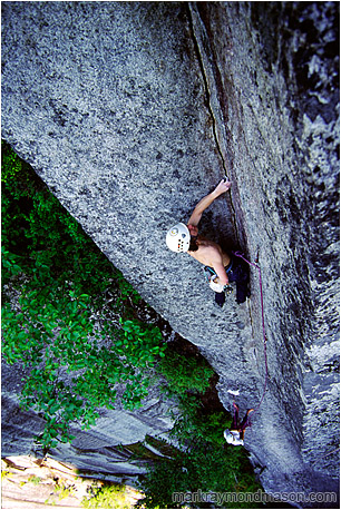 Climbing photo of a climber scaling a thin crack in a large, intimidating corner, high above the ground