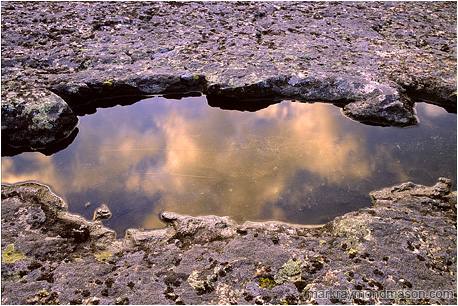 Fine art photograph of reflections in a pool of water, surrounded by textured rock