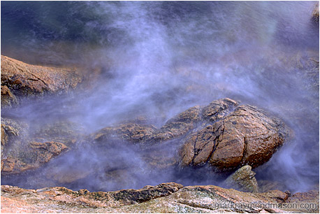 Abstract photograph of misty water crashing on a rocky shore