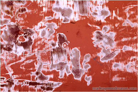 Abstract photograph of graffiti removal scratch marks and patterns on an orange painted metal doorway