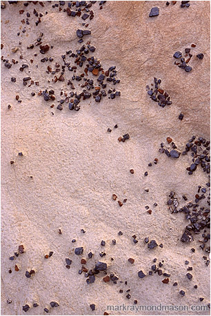 Fine art photograph of brightly coloured rocks forming a dynamic pattern on lightly toned sand