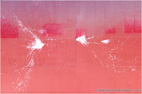 Abstract fine art photograph of arcs of white paint splashed over a dirty pink brick wall