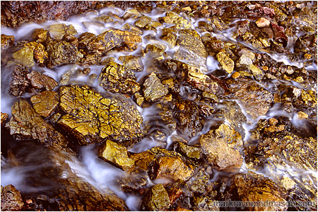 Fine art abstract photograph of an alpine stream flowing around broken yellowed limestone blocks
