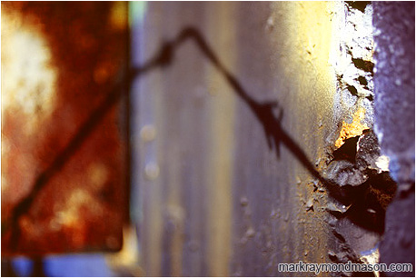 Abstract photograph of coloured, grainy brick and shadows of wire