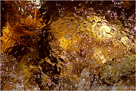 Abstract photograph of highlights and bubbles in a colourful flowing mountain creek