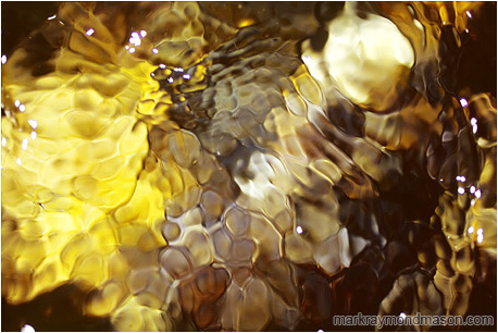 Abstract macro photograph of colourful flowing water, boiling and bubbling, highlighted by the sun