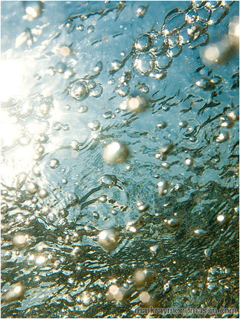 Abstract photograph of bubbles and refracted skylight from below the surface of the water