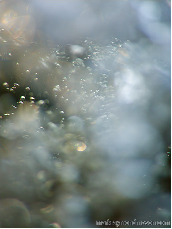 Abstract underwater photograph of dusty, clouded water revealing distant light shimmers and bubbles