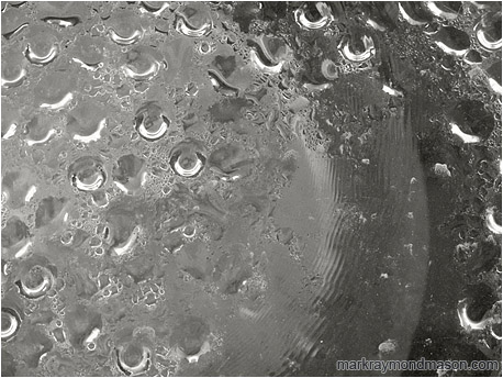 Abstract black and white photograph of beads of water on the inside of a streetlamp bulb