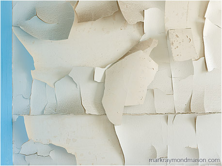 Abstract photograph of light reflecting from blue trim and spilling onto layered tiles of dirty white paint