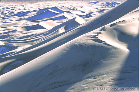 Abstract photograph of huge sand dunes, snow, and shadows deep in the desert