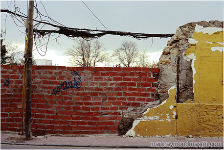 Fine art photograph of tangled wires, broken bricks, graffiti, and chipped plaster