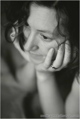 Fine art black and white photograph of a beautiful woman with her head in her hands and curled hair on her face