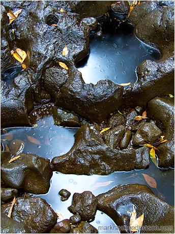 Fine art photograph of water rippling through a series of natural potholes and scattered boulders