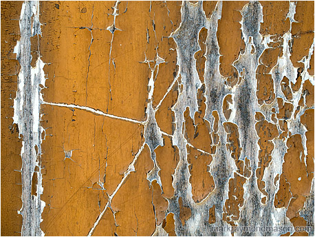 Abstract photograph showing dynamic cracks in aging paint on a wooden doorway, the worn areas looking like crackling arcs of electricity