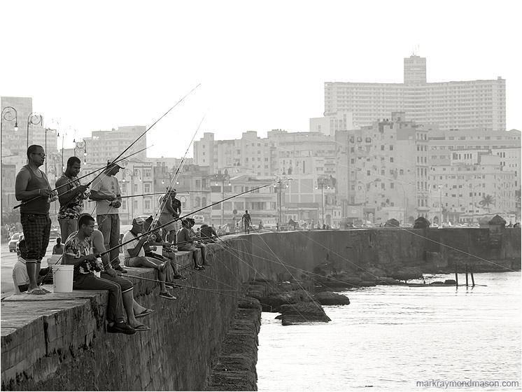 Men Fishing, Pale Skyline: Havana, Cuba (2017-02-15) - Black and white landscape photograph showing men fishing from the Malecon, with the ancient buildings of Havana in the background